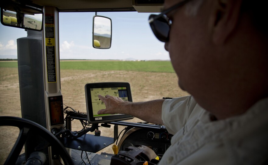 Buffett rides on John Deere planter to show how crops are planted using GPS technology.