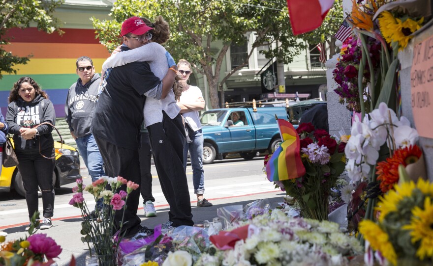 Larry Pascua hugs a friend Monday in San Francisco amid flowers and other items left as a memorial to those killed in the attack on a gay nightclub in Orlando, Fla.