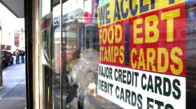 A sign in a New York City market window advertises the acceptance of food stamps.