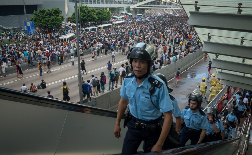 Police officers walk up an escalator after demonstrators storm onto a highway during ongoing pro-democracy protests in Hong Kong Sunday.