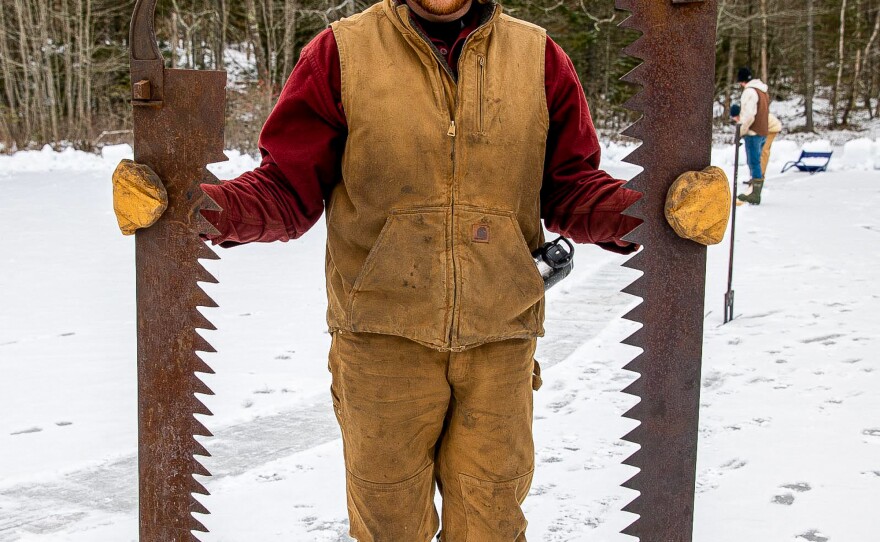 Zachary Plummer holds two pond ice cutting saws.