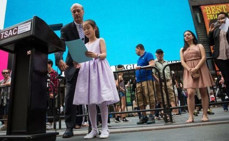 Young artist Sharon Yang told a crowd in Manhattan about her painting — assisted by Times Square Advertising Coalition president Fred Rosenberg, who held the microphone.