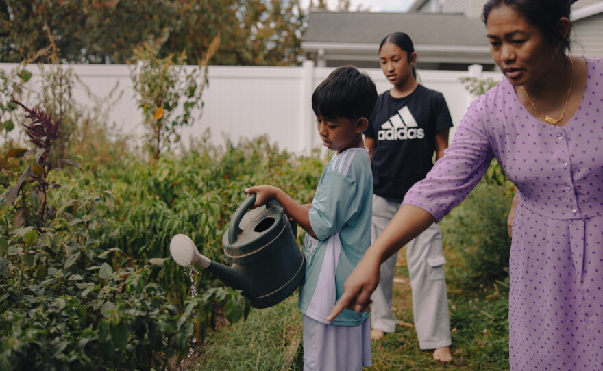 Aaron Tamang, 9, waters his family's backyard garden under the guidance of his mom, Nir Tamang, in Harrisburg, Pa., on Sept. 14, 2025. His sister, Naishi Tamang, 13, tags along.
