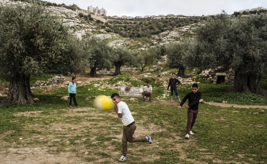 Palestinian children play in Marda, with the Jewish settlement of Ariel on the ridge in the background. Prior to the late 1970s, the land on which Ariel sits was farmed by nearby Palestinian families.