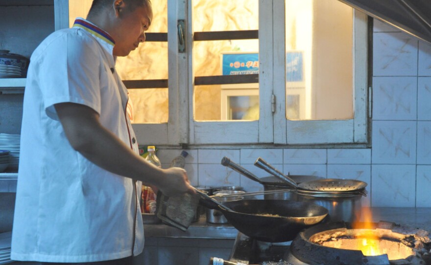 Chef Lao Wei Xiong cooks up a carry-out order for foreign reporters in the  kitchen at al Maida restaurant in Tripoli.