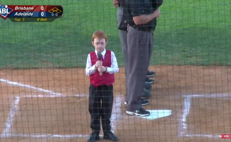 A seven-year-old boy sings the Australian national anthem before a baseball game.