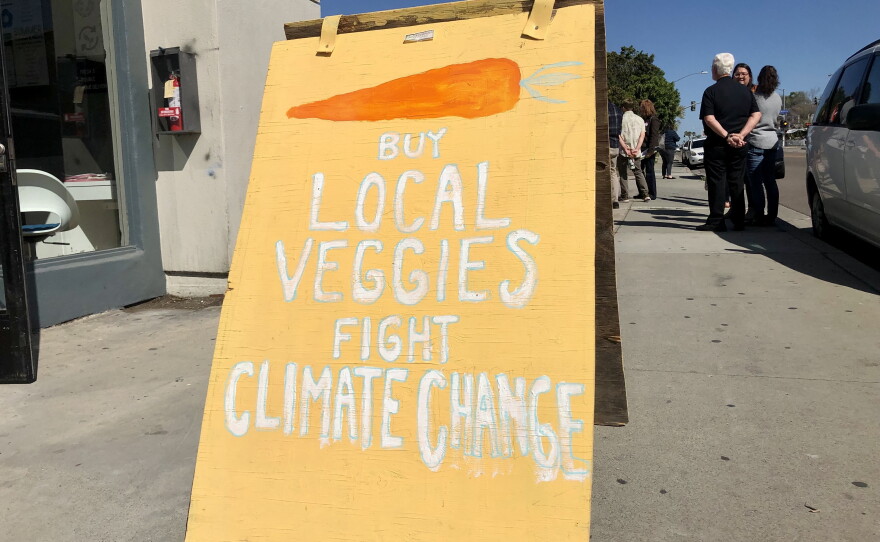A sign encouraging people to buy local vegetables to combat climate change stands outside of Foodshed Farm Hub, March 14, 2022.