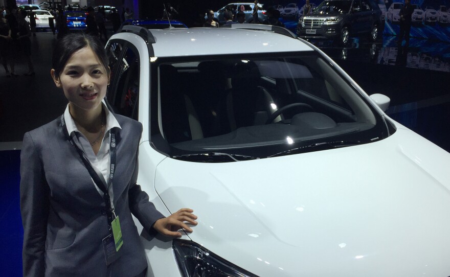 Tong Xiuying of Chinese automaker Chang'an stands in front of her automaker's first electric SUV, which will go on sale at the end of this year.