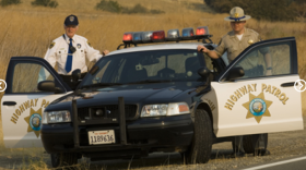 A senior volunteer (left) with the California Highway Patrol stands near a CHP vehicle during a ridealong.