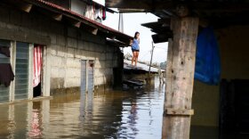 A resident stands on the roof of her house amidst flooding brought about by Typhoon Mangkhut which barreled into northeastern Philippines during the weekend and inundated low-lying areas in its 900-kilometer wide cloud band, in Calumpit township, Bulacan province north of Manila, Philippines, Sept. 17, 2018. 