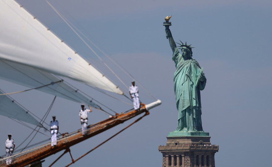 The Statue of Liberty is seen as sailors of a tall ship sail pass in the New York harbor during the International Parade of Sail, part of Sail250, a gathering of tall ships and military ships, Saturday, July 4, 2026, in New York.