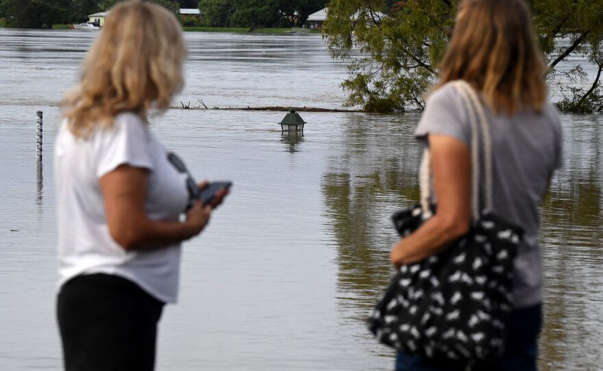 A family looks at a nearly submerged lamp post from the banks of the overflowing Clarence River in Grafton, Australia, some 80 miles from the New South Wales town of Lismore, on Tuesday.