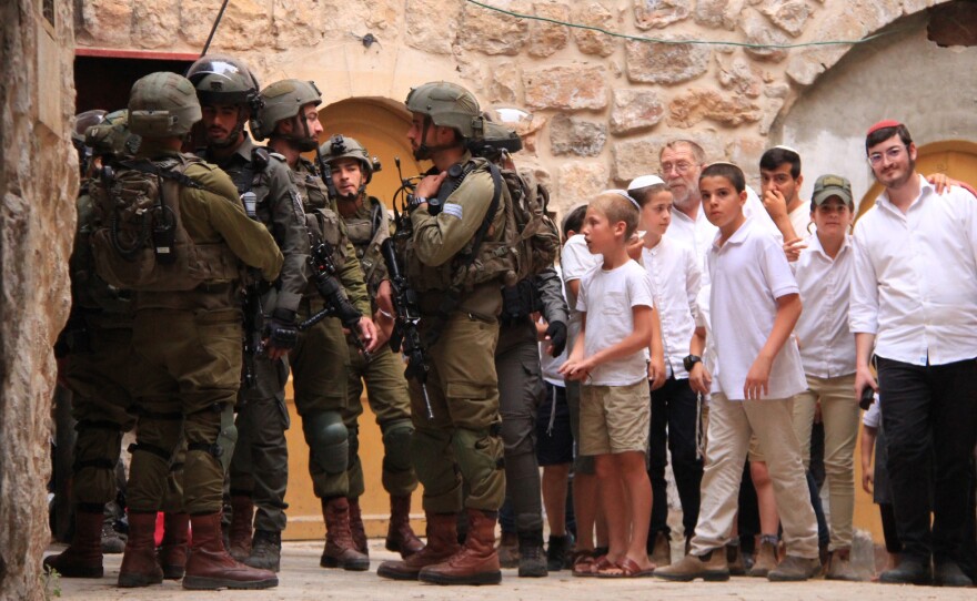 A group of Jewish settlers stands near Israeli soldiers in Hebron on May 27, 2023.
