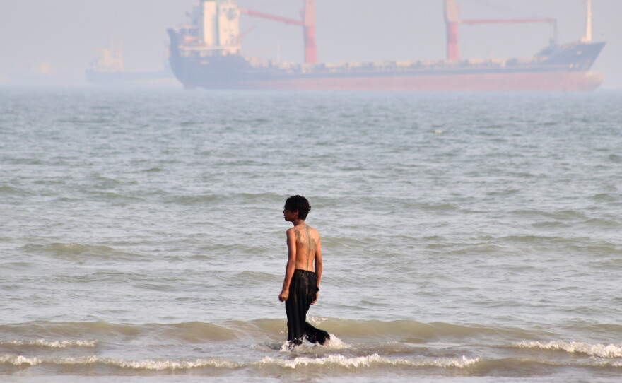 A boy walks on shallow water as commercial vessels are anchored in the Strait of Hormuz off Bandar Abbas, Iran, Monday.