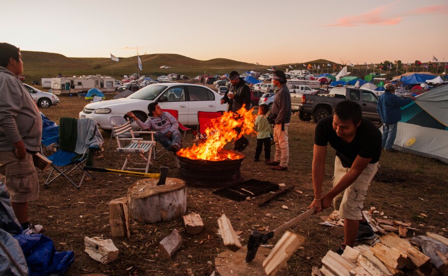 Young men chop wood at a family's camp circle in the protest camp.