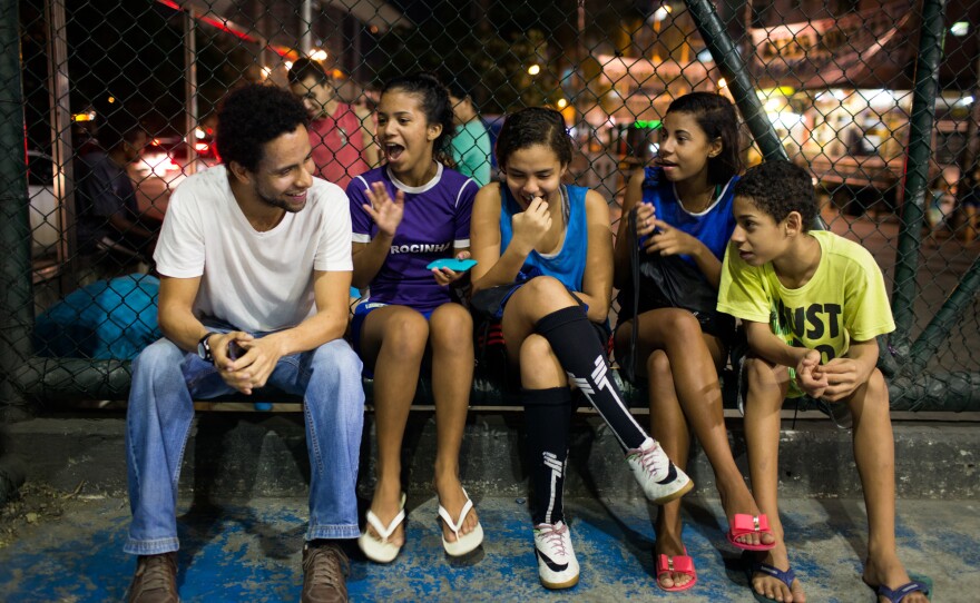 Guilherme Silva, left, is a volunteer coach with Estrela Sports, which trains girls to play soccer. He's sitting with, from left to right, Victoria Silva Rodrigues, 13, Lahis Maria Ramos Veras, 14, and Milena Medeiros dos Santos, 16, and her brother Vinicius Medeiros, 12.
