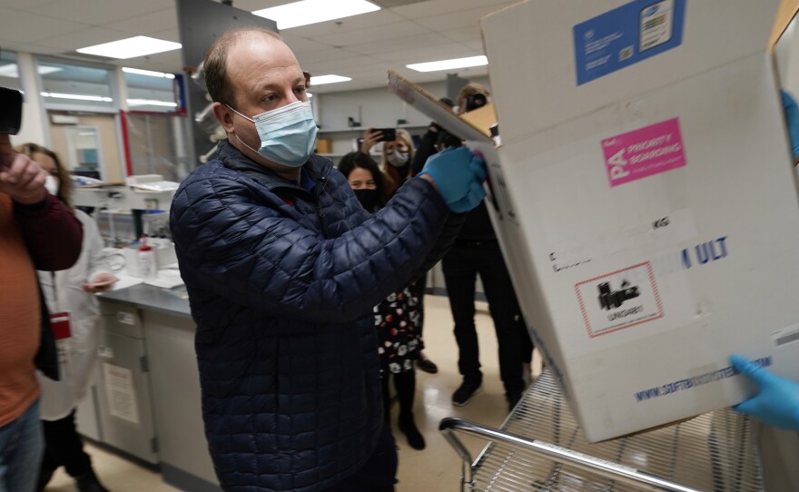 Gov. Jared Polis helps put Colorado's first shipment of COVID-19 vaccine in a freezer at a state health department laboratory last week.
