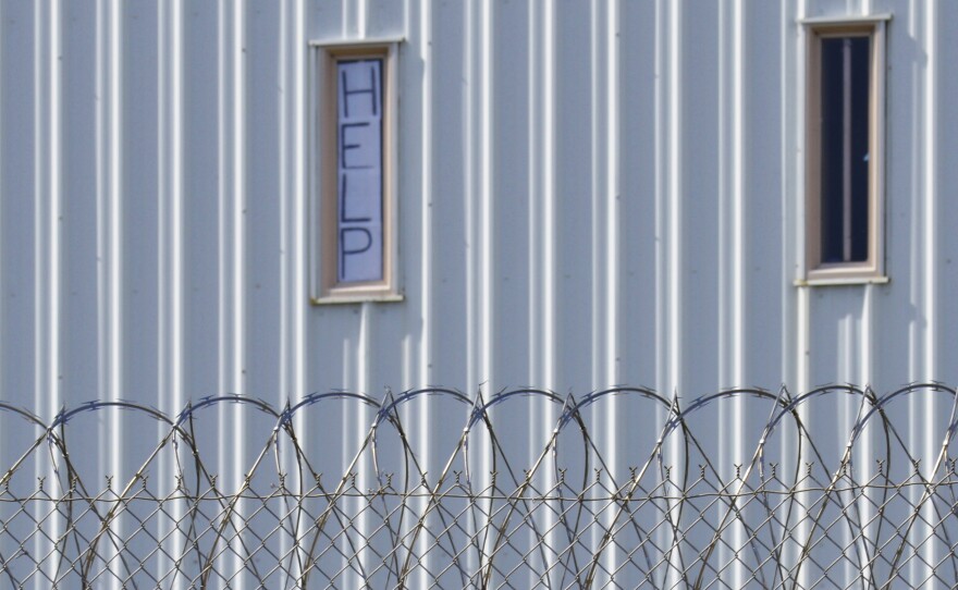 A sign placed in the window of an inmate's cell calls for "HELP" during a visit by state officials last year. Holman Correctional Facility in Atmore, Ala., long criticized for its conditions, will be largely decommissioned.