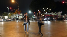 Two women cross a street in an entertainment district Thursday, Nov. 19, 2020, in Santa Monica, Calif. 