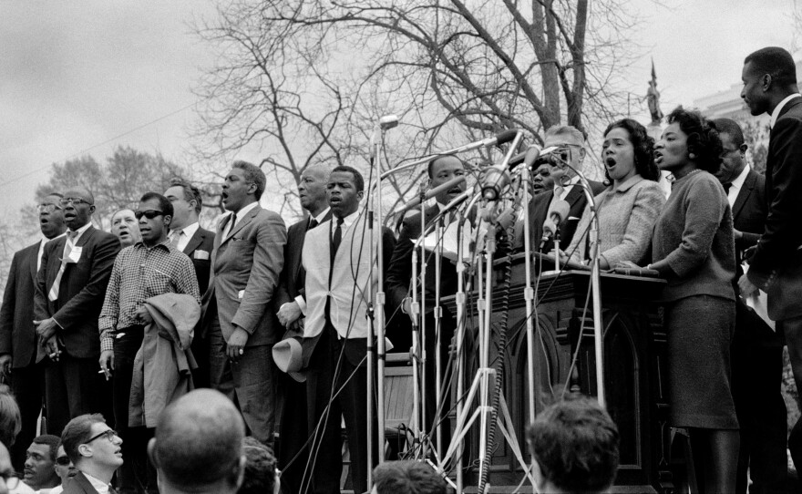 Civil rights leaders, including Dr. Martin Luther King, Jr., sing "We Shall Overcome" at the conclusion of the Selma to Montgomery civil rights march in 1965.