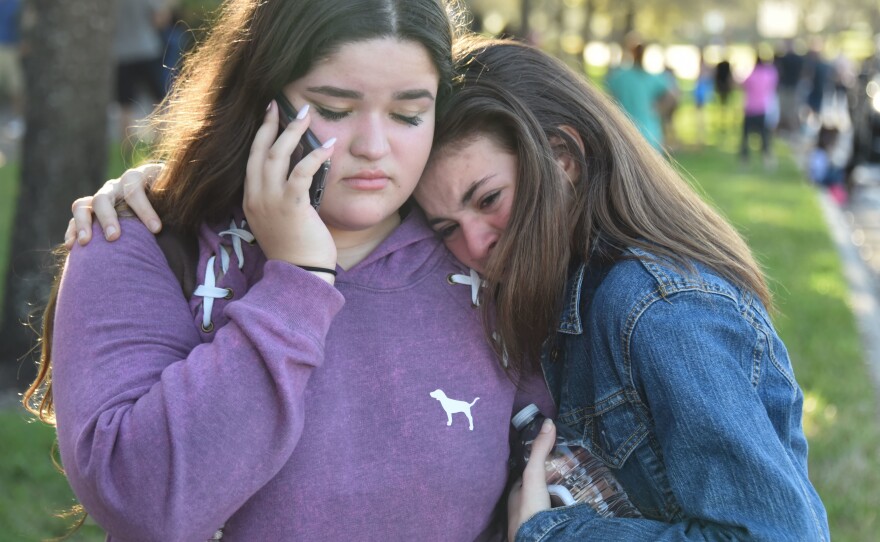 Students use their phones following the shooting at Marjory Stoneman Douglas High School in Parkland, Fla.