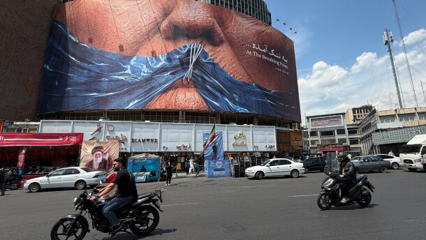 Vehicles drive past a billboard with graphic showing Strait of Hormuz and sewn lips of U.S. President Donald Trump in a square in downtown Tehran, Iran, Saturday, May 2, 2026.