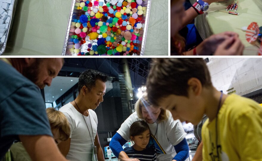 Kids participate in space-themed crafts and exercises, including trying to pick up small objects (top, left) and making their own satellites (top, right). Soraya Okely (bottom, center) gets help building a toy truck while wearing astronaut gloves as kids learn about dexterity in space.