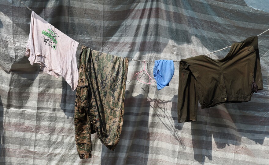 Laundry hangs near where migrant workers — all men — sleep two to three deep in corrugated metal shanties.