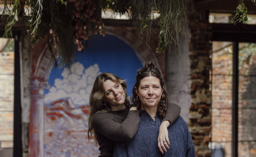Newlyweds Emma Brennan, left, and Lauren Wright stand in the first floor of their home, in front of a mural they had painted for their wedding, in Baltimore, Md. on Tuesday, Jan. 6, 2026.
