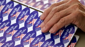 Poll worker Rosset Phan moves Vietnamese "I voted" stickers during elections in San Diego, Nov. 4, 2014.