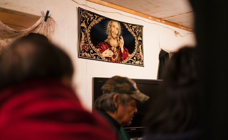 A tapestry depicting Jesus Christ hangs on the wall of a home where friends and family gather to mourn the death of a loved one in Toksook Bay in January.