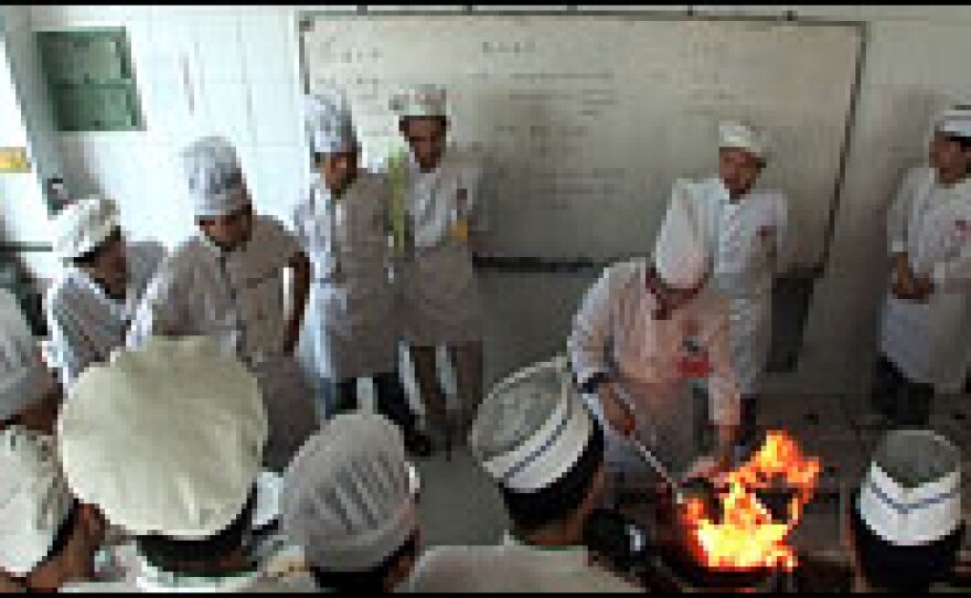 Students learn to cook on woks set over intense gas flames.