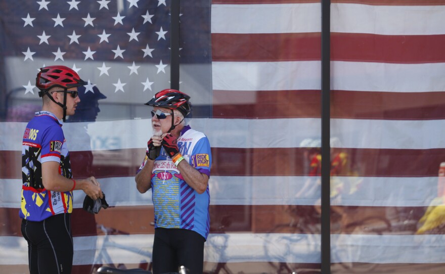 Gary Burger, 75, of West Des Moines, Iowa, puts on his helmet as he and his grandson, 21-year-old Aaron Burger of Cedar Falls, Iowa, get ready to get back on the road Wednesday, July 27, during a pit stop in Algona, Iowa. Gary Burger said he was riding with his three grandchildren and his wife. "It's just a lot of fun and gives us a chance to talk," he said.