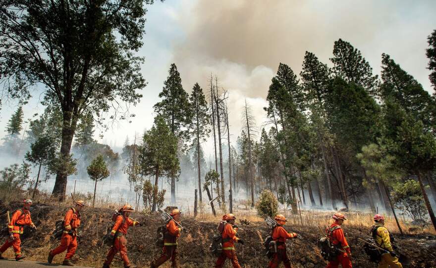 Inmate firefighters battle a California wildfire in July. Qualified inmates can volunteer to be trained in firefighting; in exchange, they are paid $2 a day and an extra $1 per hour when fighting fires. The inmate firefighters also receive sentence reductions.