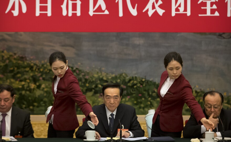 Attendants refill teacups as Chen Quanguo (center), Communist Party secretary of China's Xinjiang Uighur Autonomous Region, listens to a speaker during a group discussion meeting on the sidelines of the National People's Congress at the Great Hall of the People in Beijing, on March 12, 2019. The Politburo member is one of the subjects of new U.S. sanctions over human rights abuses in the region.