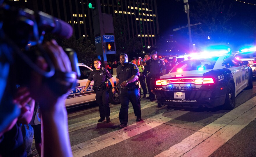 Bystanders stand near police barricades following the sniper shooting in Dallas on Thursday.