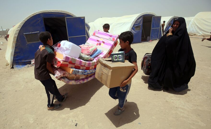 Iraqis displaced from the city of Fallujah collect aid distributed by the Norwegian Refugee Council, which has been awarded this year's $2.5 million Conrad N. Hilton Humanitarian Prize.