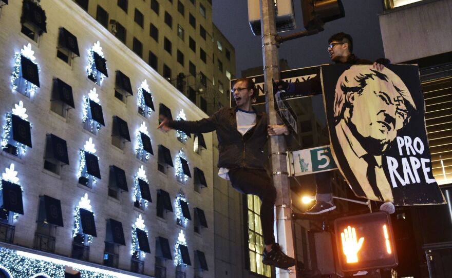 Protestors shout slogans from a lamppost during in a demonstration on 5th Avenue across from Trump Tower on Wednesday, after Donald Trump was elected as the next president of the U.S.