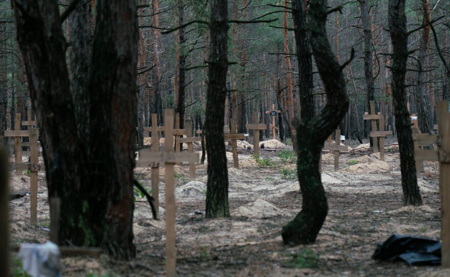 Wooden crosses mark burials at a mass grave site in newly liberated Izium, Ukraine. Some of the graves have a name and date written in thick black marker, others have simply a number scrawled across — unidentified.