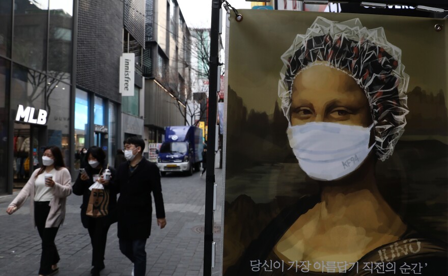 South Korea's KF94 mask does a good job concealing the <em>Mona Lisa</em>'s smile — but how effective is it at preventing coronavirus spread? Here, masked pedestrians stroll through a shopping district in Seoul.