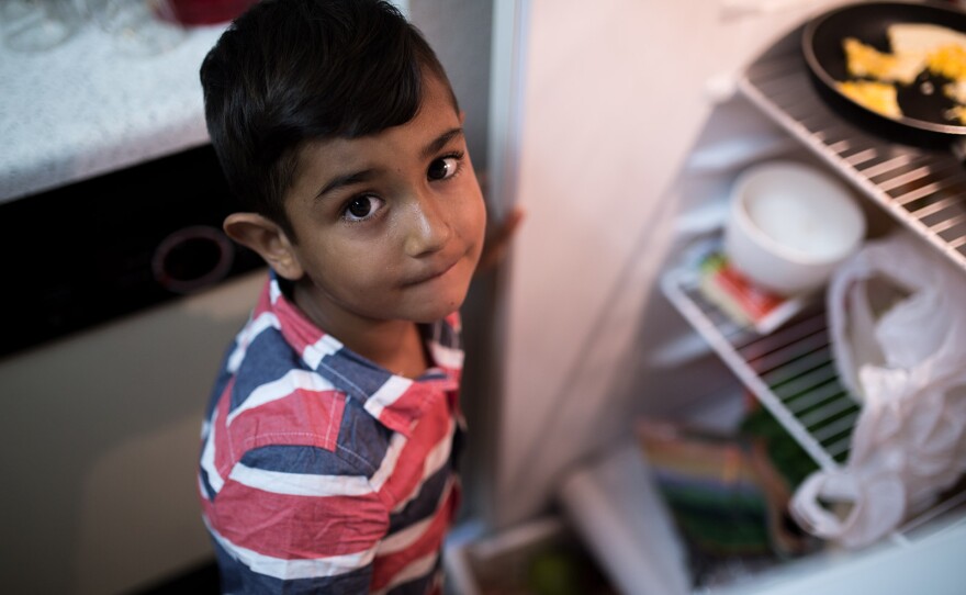 Daliya Ali's oldest son looks up from peeking into the refrigerator in his family's two-bedroom El Cajon apartment, July 25, 2017.