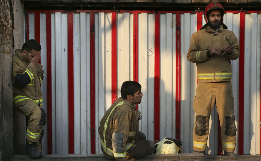 Firefighters stand outside the rubble of the Plasco building on Thursday. Firefighters, soldiers and other emergency responders dug through the ruins of Tehran's oldest high-rise, looking for survivors.