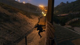 A Honduran youth jumps from the U.S. border fence, as seen from Tijuana, Mexico, on Friday, Dec. 21, 2018. 