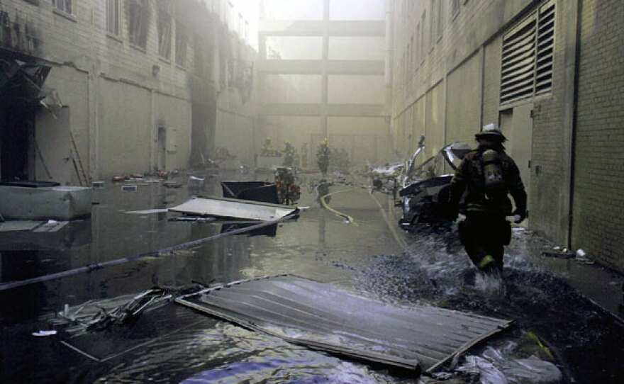 The Pentagon post 9/11 attack. First responders walk through "AE" Drive. Punchout hole made by plane in background.
