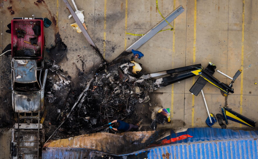In this aerial view, people investigate the aftermath of a news helicopter crash in Chatsworth, a neighborhood in Los Angeles, on Wednesday, Sept. 16, 2026.