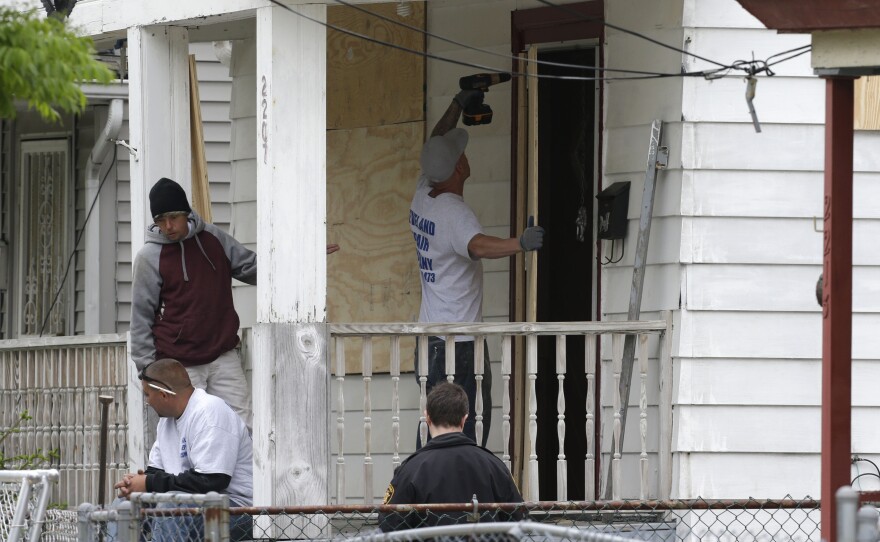 Workers board up the house where three women were held in Cleveland Saturday. Suspect Ariel Castro, who allegedly held three women captive for nearly a decade, is charged with rape and kidnapping. Sunday, the women asked for privacy and time to connect with their families.