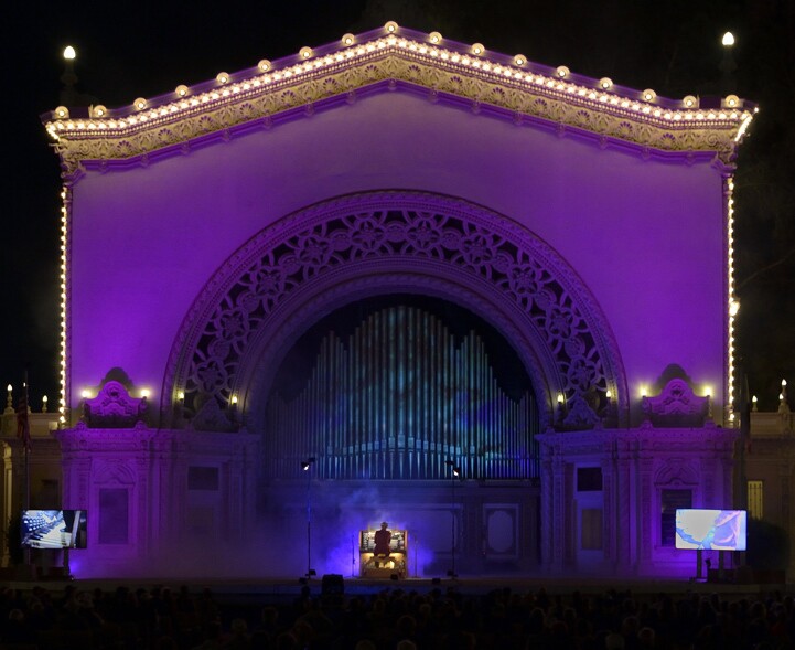 The Spreckels Organ Pavilion is shown illuminated in bright purple for a Halloween performance.