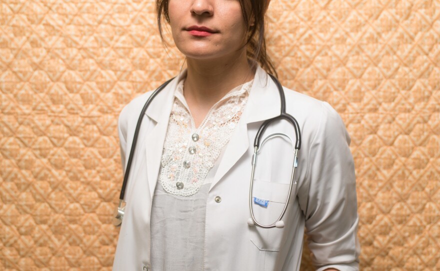 Hozan Badeea Sindi, now 27, stands in front of the blanket she slept under during her many months as an intern at a hospital in the Kurdish region of Iraq.