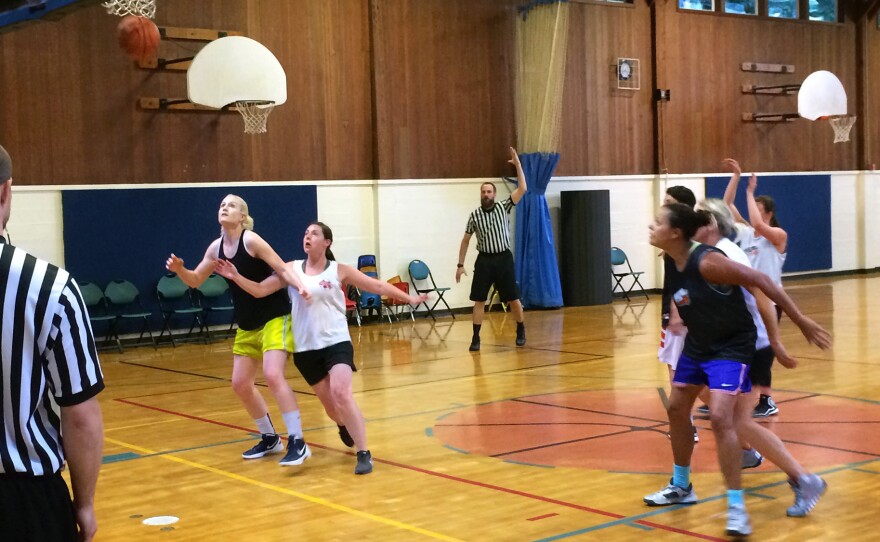 Lei Hart, in black jersey and blue shorts, boxes out an opponent on a free throw attempt. Hart, 41, plays every Monday night at the Hillside Community Center in Portland, Ore.