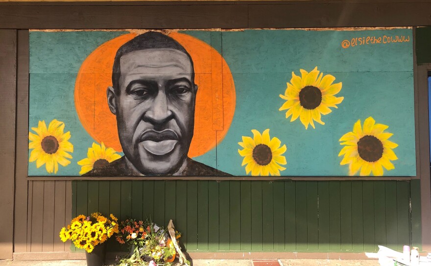A mural of George Floyd, painted by artist Chloe Becky, covers the plywood boards on the shattered storefront of a beauty college in La Mesa on June 2, 2020.
